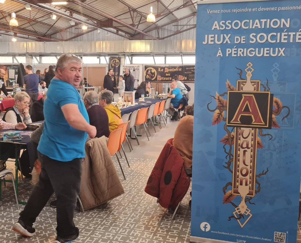 Francis Vincent dans son t-shirt bleu d'Avalon devant l'oriflamme de l'association